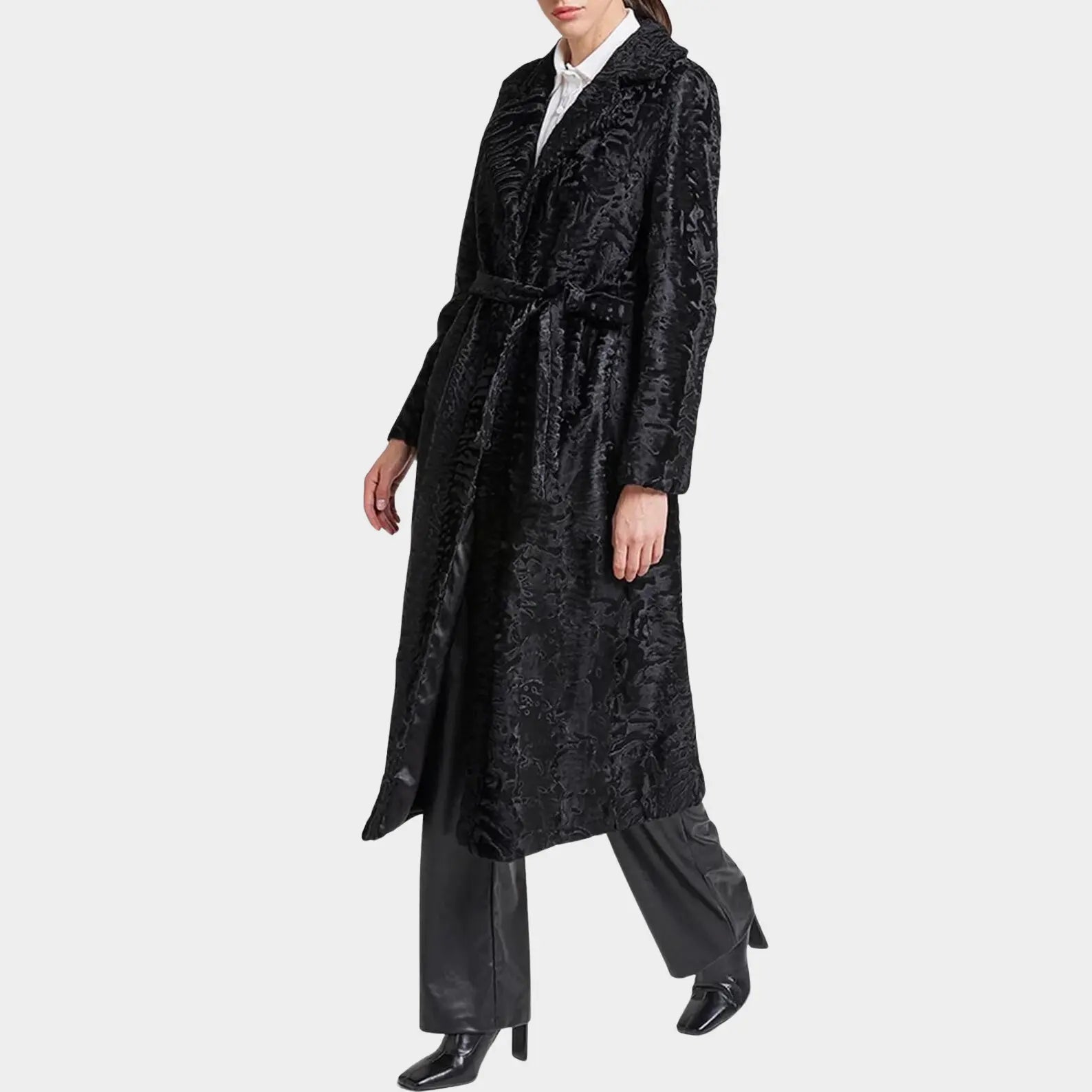 Person wearing a long black textured coat on a white background