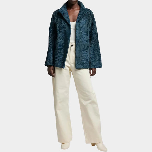 Person wearing a teal textured coat and white pants on a light gray background