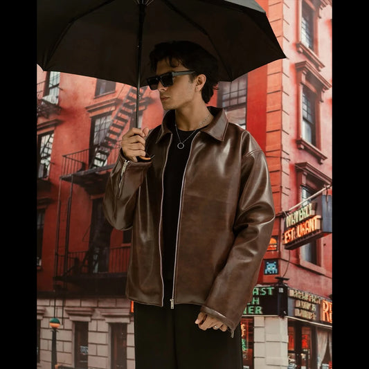 Person wearing a brown leather jacket holding a black umbrella against a cityscape background