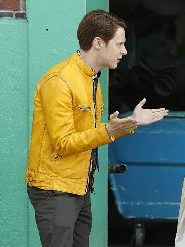 Man in a yellow jacket standing against a teal and blue wall