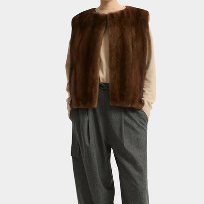 Brown fur vest over a beige shirt and gray pants on a white background