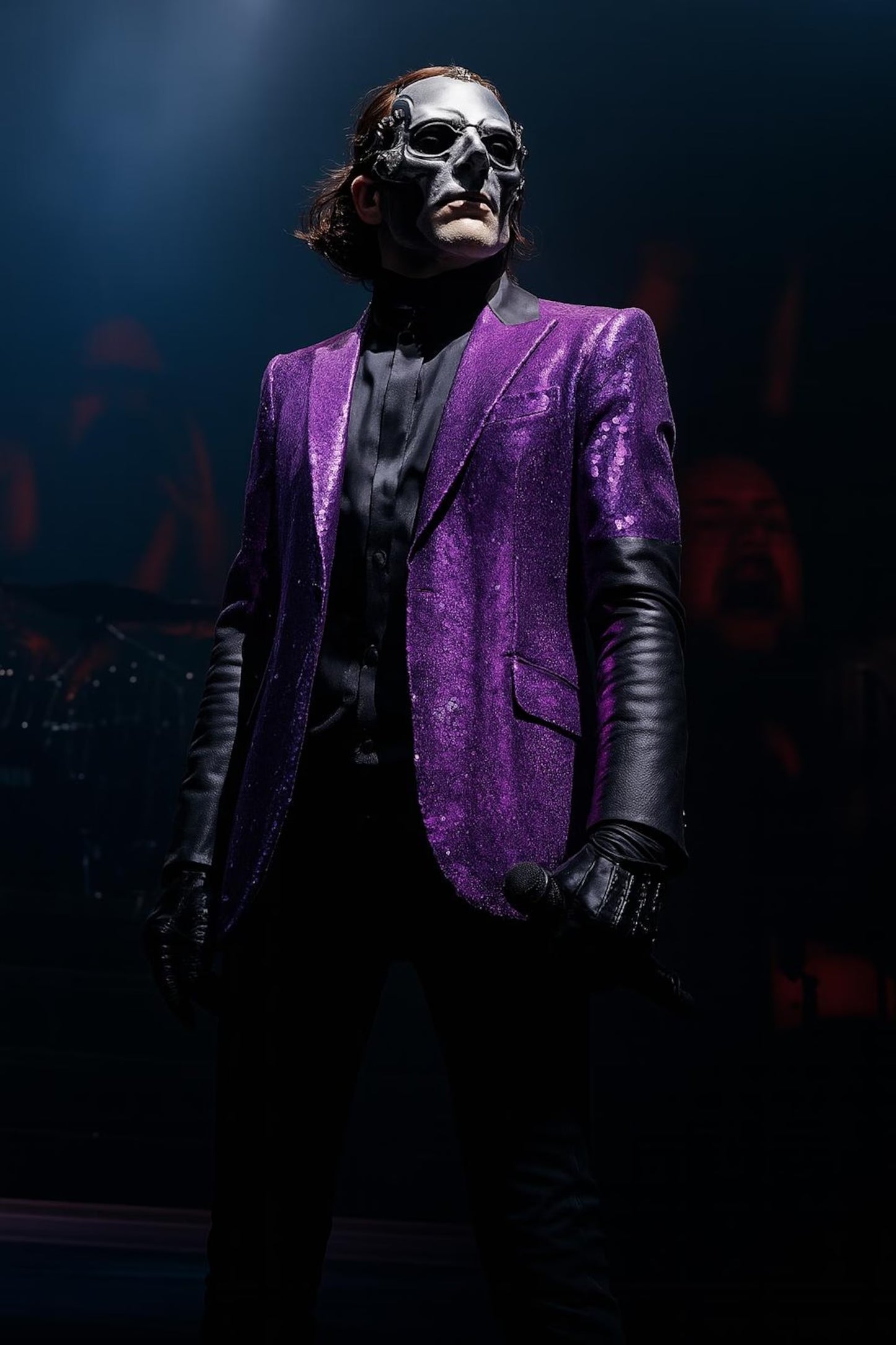 Person wearing a purple suit and black mask in a dark setting