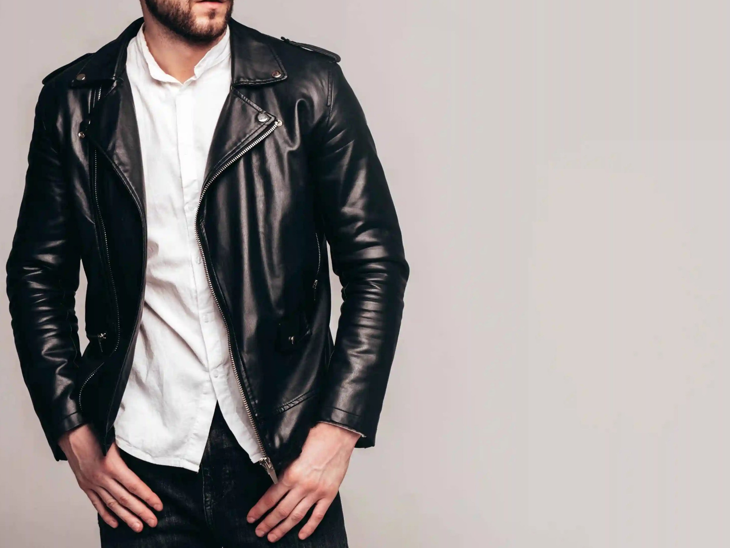 Man wearing a black leather jacket and sunglasses against a plain background