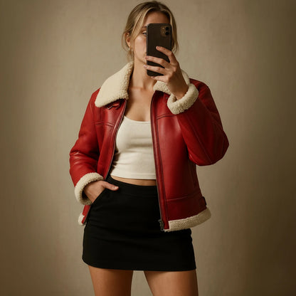 Person wearing a red jacket with white fur lining, taking a mirror selfie.